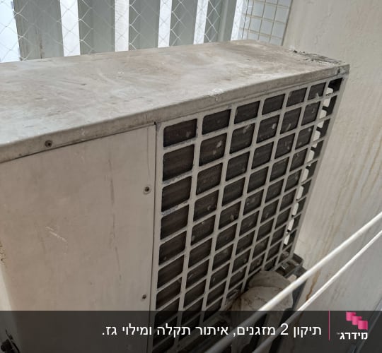 יחידת מזגן חיצונית עם סורגי אוורור על קיר חיצוני